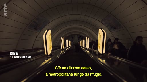 Le 31 décembre 2022 à Kiev, des civils se réfugient dans une station de métro utilisée comme abri anti-aérien pendant la guerre en Ukraine. La scène montre les escaliers mécaniques d'une station souterraine éclairée par des panneaux publicitaires.