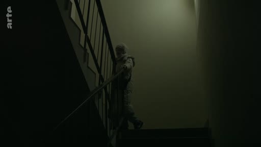 Une silhouette humaine descend un escalier dans une ambiance sombre et isolée, évoquant un sentiment de solitude ou de mystère.