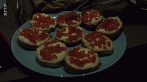 Une assiette remplie de tartines au caviar rouge, typiques de la cuisine ukrainienne, présentée lors d'un repas familial en soirée.