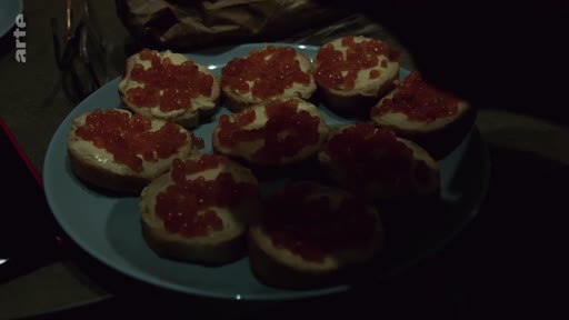 Une assiette remplie de tartines garnies de caviar rouge, typiques de la cuisine ukrainienne, lors d'un repas en soirée dans un foyer ukrainien.