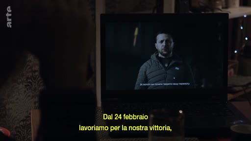 Le président ukrainien Volodymyr Zelensky apparaît sur l'écran d'un ordinateur portable dans un intérieur domestique. Une légende en italien souligne l'effort de guerre depuis le 24 février.