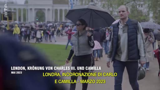 Des personnes marchent dans les rues de Londres sous des parapluies lors du couronnement du roi Charles III et de la reine Camilla en mai 2023. Le texte à l'écran indique 'London, Krönung von Charles III. und Camilla' et 'Londra, incoronazione di Carlo e Camilla'.
