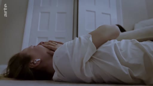 Une jeune femme est allongée sur le sol, portant des écouteurs sans fil, dans une posture d'introspection ou de méditation existentielle. L'image illustre un moment de solitude, de réflexion personnelle ou de détresse psychologique dans un cadre domestique.