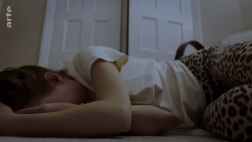 Une jeune femme allongée sur un lit, le visage caché, dans une atmosphère sombre et mélancolique, illustrant la détresse psychologique ou le deuil dans le contexte du conflit en Ukraine.