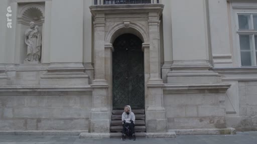 Une personne solitaire est assise sur les marches d'une église en pierre en Ukraine, illustrant l'atmosphère de recueillement et de deuil dans le pays.