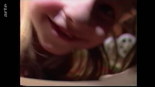 Gros plan sur le visage d'une jeune enfant souriante, extrait d'une séquence d'archives illustrant des souvenirs d'enfance.