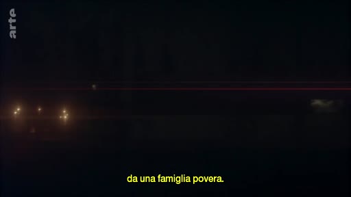 Vue nocturne d'un paysage sombre avec des lumières lointaines, accompagnée d'un sous-titre en italien mentionnant une famille pauvre.