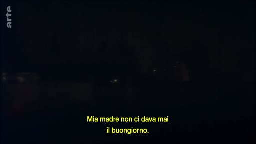 Une image très sombre avec le sous-titre italien 'Mia madre non ci dava mai il buongiorno' affiché à l'écran, évoquant un récit personnel ou un témoignage.