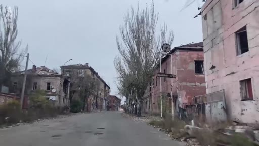 Vue d'une rue déserte bordée d'immeubles résidentiels gravement endommagés par la guerre en Ukraine, témoignant de la destruction urbaine.
