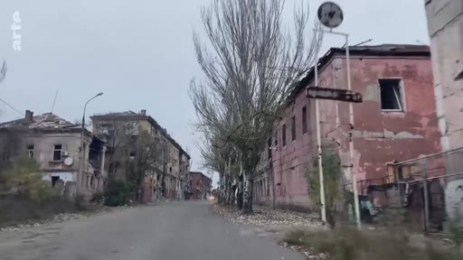 Vue d'une rue résidentielle en Ukraine montrant des immeubles d'habitation gravement endommagés par les combats, illustrant les destructions urbaines liées au conflit en cours.