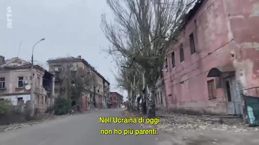 Vue d'une rue bordée de bâtiments endommagés et en ruines en Ukraine, illustrant les conséquences du conflit actuel. Le sous-titre indique le témoignage d'une personne n'ayant plus de famille dans le pays.
