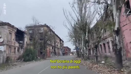 Vue d'une rue bordée de bâtiments résidentiels gravement endommagés par les combats en Ukraine, illustrant les conséquences de la guerre. Le texte à l'écran souligne la perte de liens familiaux dans le pays.