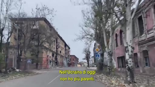Vue d'une rue bordée d'immeubles résidentiels gravement endommagés par les combats en Ukraine, illustrant les conséquences du conflit actuel. Le texte à l'écran souligne la perte de liens familiaux dans le pays.