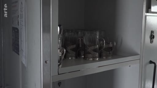 Des verres à thé typiques avec leurs porte-verres en métal, emblématiques des voyages en train en Russie et en Ukraine, sont disposés sur une étagère à bord d'un wagon.