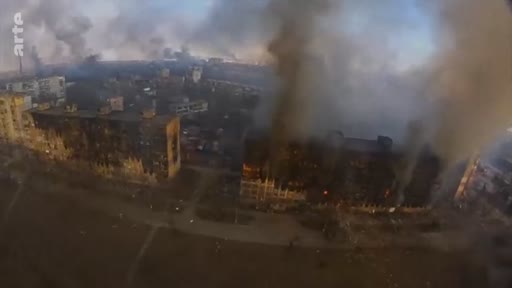 Vue aérienne montrant des immeubles résidentiels en flammes et dévastés par les bombardements à Marioupol, en Ukraine. Cette image illustre la destruction urbaine causée par le conflit armé.
