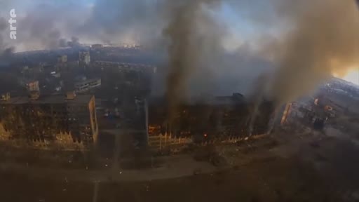 Vue aérienne montrant un immeuble résidentiel en proie aux flammes et à la fumée lors du siège de Marioupol en Ukraine. Les destructions urbaines témoignent de l'intensité des combats dans la ville.