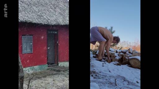 Un homme torse nu ramasse du bois de chauffage dans un environnement enneigé, à côté d'une maison traditionnelle aux murs rouges. Cette scène illustre le quotidien rustique et les conditions de vie hivernales dans une communauté villageoise.