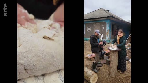 Une femme prépare de la pâte à pain sur un support en bois en extérieur, filmée par un caméraman devant une maison de village. Cette scène illustre les activités quotidiennes et les traditions culinaires dans un contexte rural.