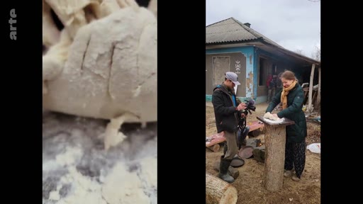 Une femme prépare de la pâte sur un support en bois à l'extérieur d'une maison traditionnelle, filmée par un caméraman dans un village. Cette scène illustre les activités quotidiennes et les traditions culinaires locales.