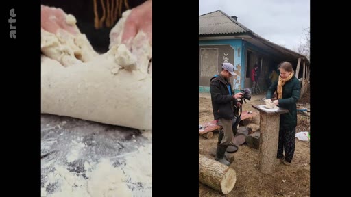 Une femme pétrit de la pâte sur un billot de bois en extérieur, filmée par un caméraman dans un village. Cette scène illustre les conditions de vie et les activités quotidiennes dans une zone rurale, potentiellement en Ukraine, documentée par la chaîne Arte.