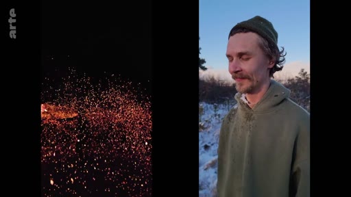 Un homme portant un bonnet et un sweat-shirt à capuche se tient debout dans un paysage enneigé, avec un feu de camp crépitant visible sur la gauche de l'image. Cette scène illustre le quotidien dans des conditions difficiles, potentiellement lié au conflit en Ukraine.