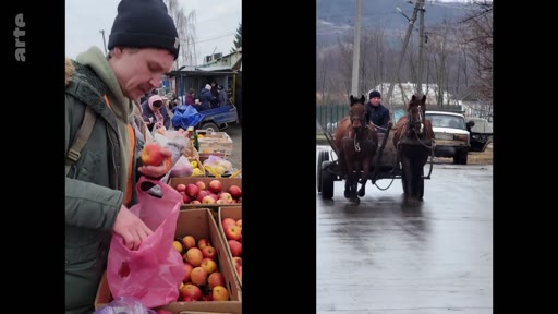Un homme en bonnet choisit des pommes sur un étal de marché en extérieur, illustrant la vie quotidienne et l'adaptation aux conditions locales, avec une charrette tirée par deux chevaux circulant sur la route en arrière-plan.