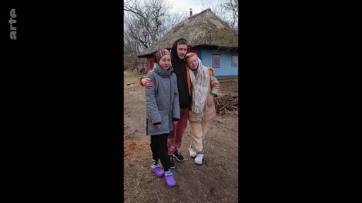 Trois jeunes personnes posent ensemble devant une maison traditionnelle en Ukraine, dans un contexte de conflit et de mobilisation militaire. Cette image illustre la vie quotidienne et les liens familiaux dans les zones rurales ukrainiennes touchées par la guerre.