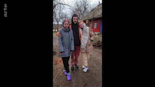 Trois jeunes personnes, deux femmes et un homme, posent ensemble pour une photo devant une maison rurale lors d'un moment de vie quotidienne, possiblement lié à un contexte de départ ou de séparation.