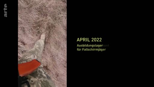 Un soldat en tenue de camouflage et équipé d'une arme marche dans un champ lors d'un camp d'entraînement pour parachutistes en avril 2022. L'image illustre la préparation militaire des troupes.