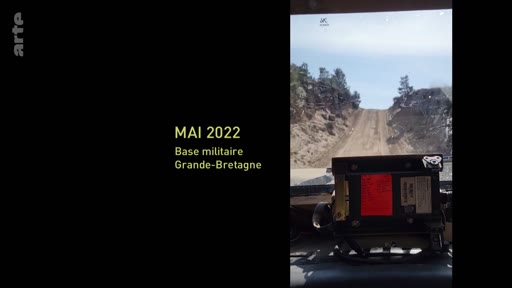 Vue subjective depuis l'intérieur d'un véhicule militaire circulant sur un terrain d'entraînement en Grande-Bretagne en mai 2022. Le texte à l'écran indique la date et le lieu de l'exercice militaire.