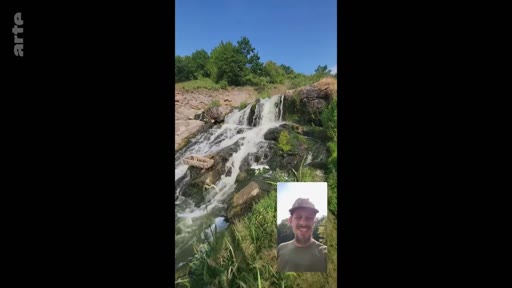 Un homme souriant apparaît en médaillon lors d'un appel vidéo, avec en arrière-plan une cascade naturelle dans un paysage verdoyant.