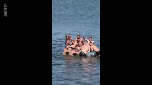 Un groupe de soldats russes en tenue décontractée profite d'un moment de détente sur un bateau pneumatique au milieu d'un plan d'eau, illustrant la vie quotidienne et la camaraderie au sein des troupes.