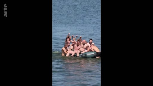 Un groupe de soldats torse nu s'amuse et pose joyeusement sur un canot pneumatique gonflable en pleine mer, illustrant des moments de camaraderie et de détente au sein de l'armée.