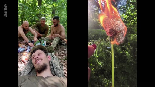 Des soldats ukrainiens en tenue de camouflage se reposent dans une zone boisée, filmés en mode selfie, tandis qu'une fleur est brûlée par une flamme au premier plan. Cette séquence illustre le quotidien des militaires sur le front ukrainien.
