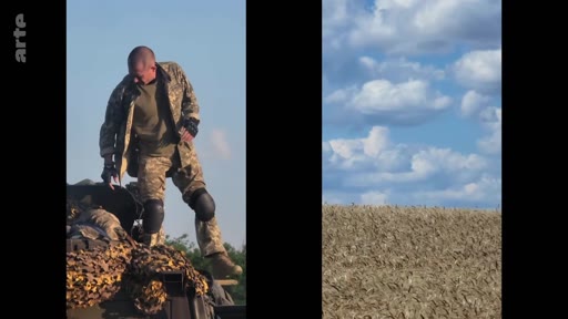 Un soldat ukrainien en uniforme de combat et genouillères monte sur un véhicule militaire recouvert d'un filet de camouflage dans un champ. Cette image illustre le quotidien des troupes ukrainiennes sur le front lors du conflit en Ukraine.