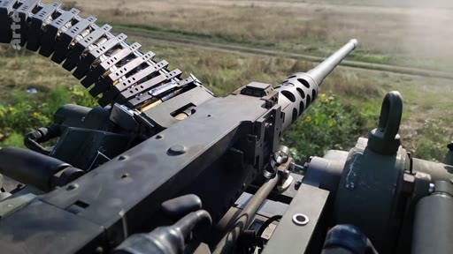 Vue à la première personne depuis un véhicule militaire montrant une mitrailleuse lourde Browning M2 avec sa bande de munitions, utilisée dans un contexte de combat ou d'entraînement.