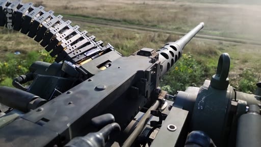 Vue à la première personne depuis un véhicule militaire montrant une mitrailleuse lourde Browning M2 avec sa bande de munitions, utilisée dans un contexte de combat ou d'entraînement.