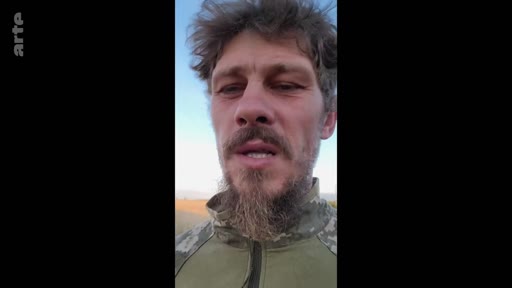 Un soldat ukrainien en tenue de camouflage s'exprime face caméra lors d'un témoignage vidéo, probablement depuis le front en Ukraine. Le soldat porte une barbe et semble s'adresser directement à son audience dans un contexte de conflit armé.