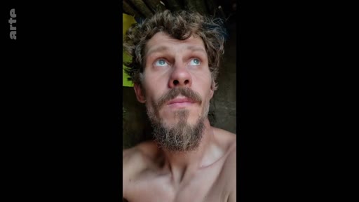 Un soldat barbu, filmé en gros plan, regarde vers le haut alors qu'il se trouve dans une tranchée. Cette image illustre le quotidien difficile et l'isolement des soldats sur le front.