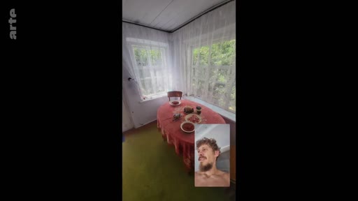 Un homme barbu, torse nu, apparaît en médaillon lors d'un appel vidéo, tandis qu'en arrière-plan, une pièce lumineuse avec une table recouverte d'une nappe rouge est visible. Cette image illustre les liens familiaux maintenus à distance dans un contexte de conflit.
