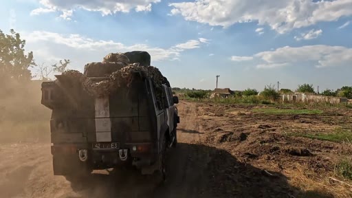 Un véhicule militaire, potentiellement un camion de transport, circule sur un chemin de terre dans un paysage rural, illustrant le contexte de la guerre en Ukraine et la progression des forces dans les zones libérées.