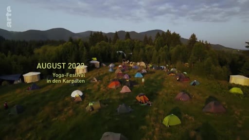 Vue aérienne d'un campement de tentes lors d'un festival de yoga organisé dans les Carpates en août 2022. L'image montre une multitude de tentes installées dans une zone montagneuse verdoyante.