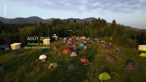 Vue aérienne d'un rassemblement de tentes et de yourtes dans une zone montagneuse lors d'un festival de yoga dans les Carpates en août 2022. L'image illustre un événement de plein air en pleine nature.