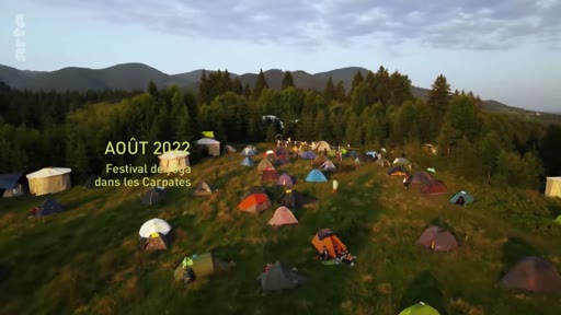 Vue aérienne d'un rassemblement de tentes et de yourtes dans une zone montagneuse lors d'un festival de yoga dans les Carpates en août 2022. L'image illustre un événement de plein air dans un cadre naturel.