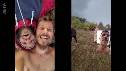 Un homme torse nu filme un appel vidéo en extérieur, montrant son visage et celui d'un autre homme en gros plan, tandis qu'en arrière-plan, des personnes marchent dans un champ lors d'une sortie en plein air.