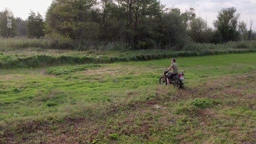 Un homme circule à moto à travers un champ dans la région de Kherson, illustrant le quotidien dans les zones libérées après le retrait des forces russes.