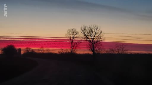 Vue panoramique d'un paysage rural au crépuscule avec un ciel rougeoyant, illustrant l'atmosphère dans la région du Donbass pendant le conflit.