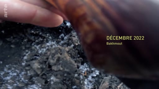 Une main fouille dans des débris calcinés à Bakhmout, en Ukraine, en décembre 2022, illustrant les destructions causées par la guerre.