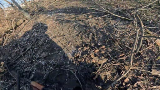 Un soldat armé patrouille dans un paysage dévasté et jonché de débris, probablement dans les environs de Bakhmout en Ukraine, illustrant la réalité du conflit sur le terrain.