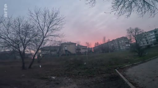Vue d'ensemble d'un quartier résidentiel avec des immeubles d'habitation sous un ciel crépusculaire, illustrant le contexte urbain dans une zone potentiellement touchée par un conflit.